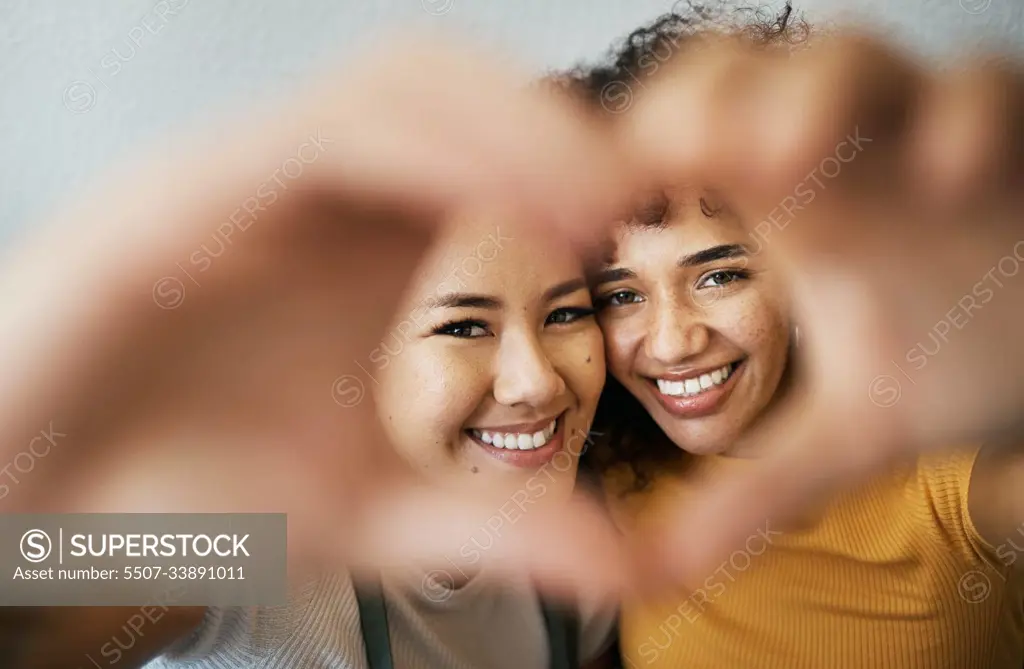 Heart, hands and portrait of happy lesbian couple for care, trust and support in relationship at home. Love sign, face and gay women together in commitment to marriage, connection and LGBTQ or emoji