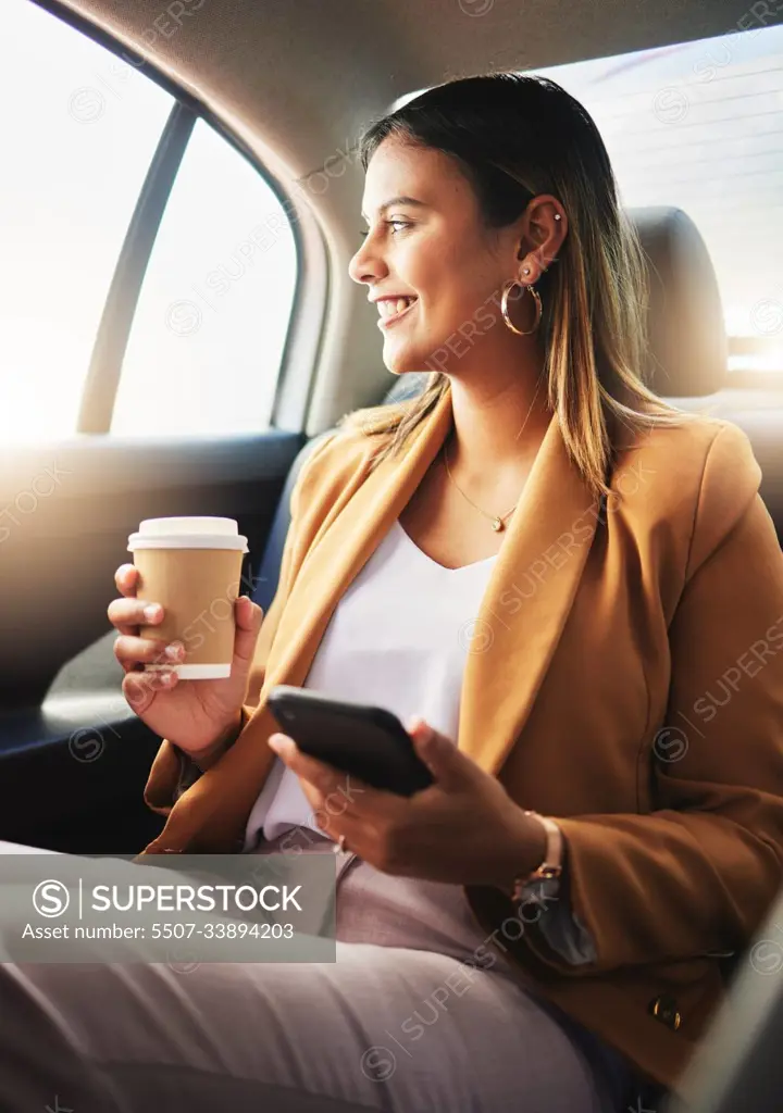 Businesswoman, phone and coffee in car for travel to work with smile in happiness, alone and profile. Young, person and employee with commute to office in taxi, backseat and sitting to look at street