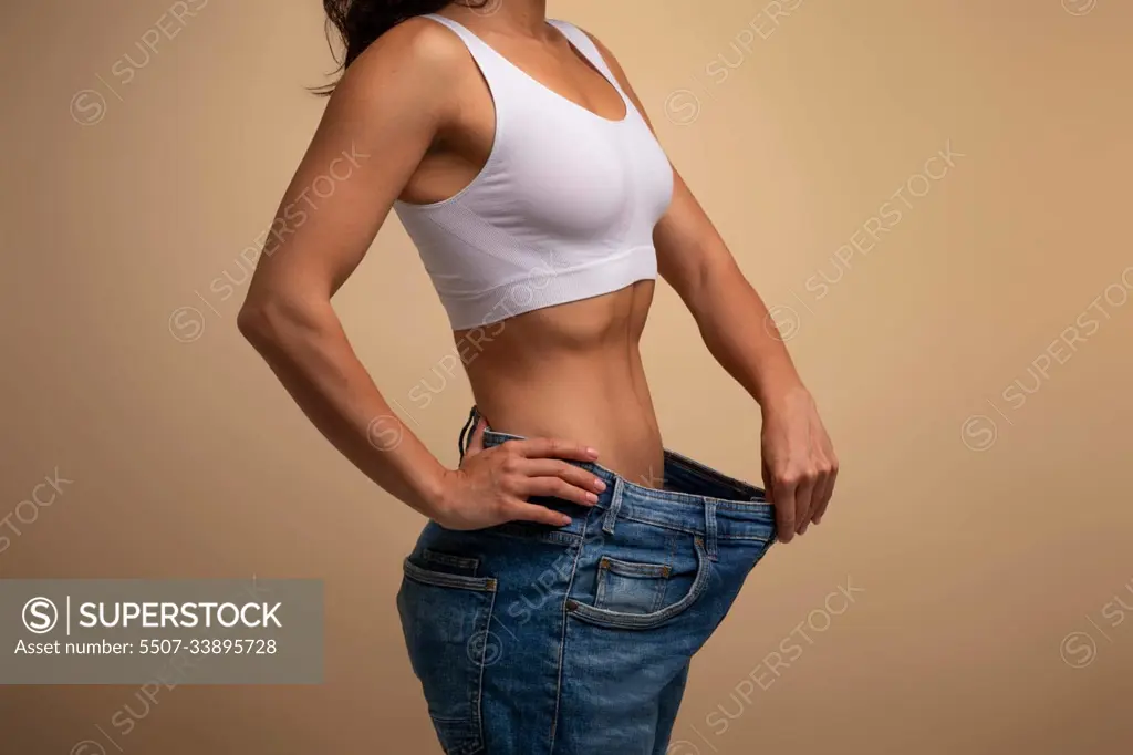 Cropped of lady in big jeans demonstrating results of diet