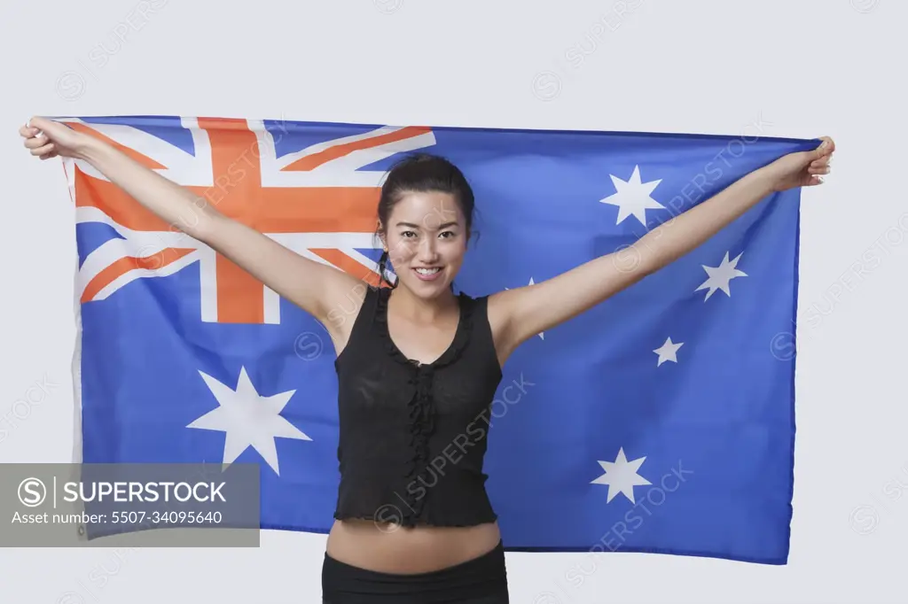 Portrait of smiling young woman holding Australian flag over white background