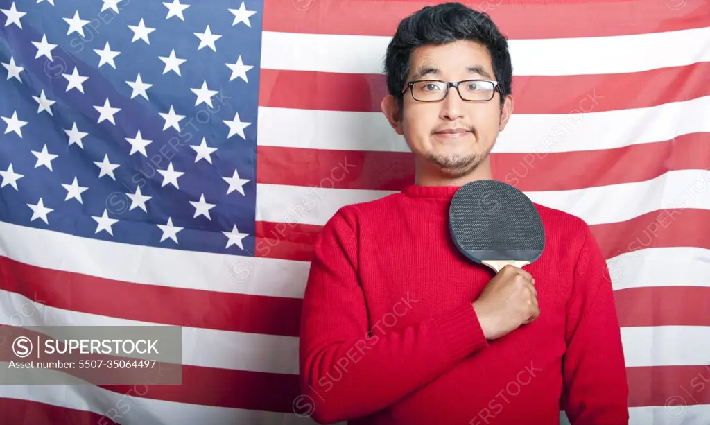 Proud Asian Man holding table tennis paddle against US Flag