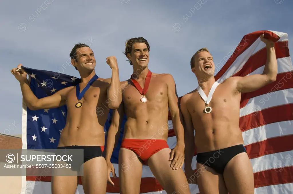 Victorious male athletes cheering up while holding an American flag