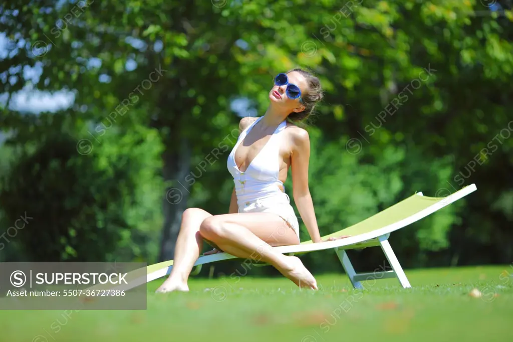 girl sitting in a white lounge on a green grass