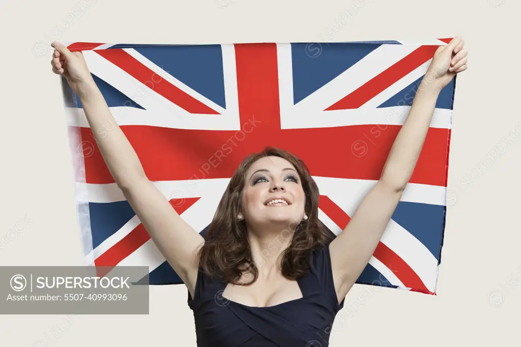 Young woman holding British Flag with pride over gray background