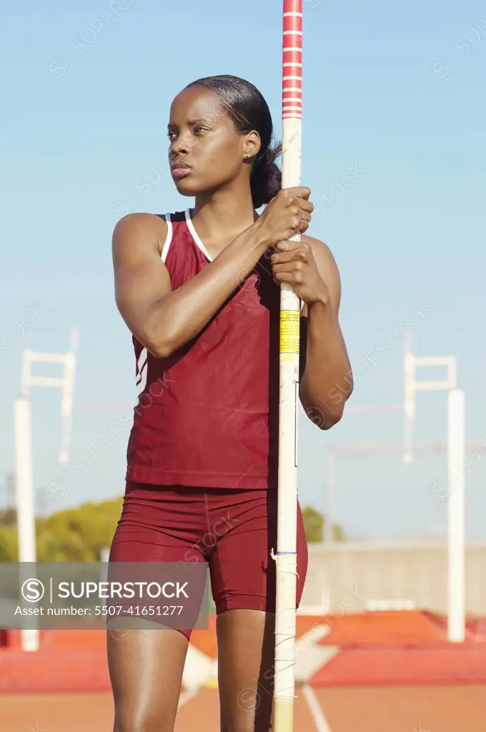 African American female pole vaulter holding pole on track and field