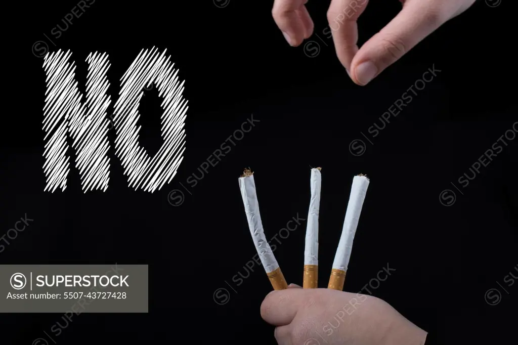 Hand is holding  cigarettes on black background