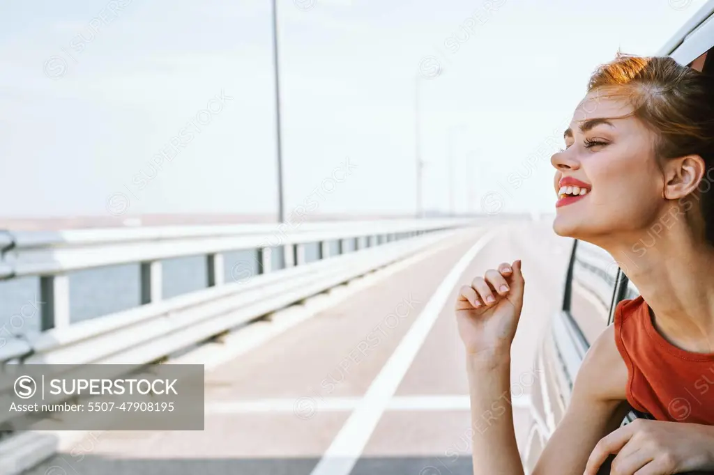 cheerful woman peeking out of the car window trip road travel