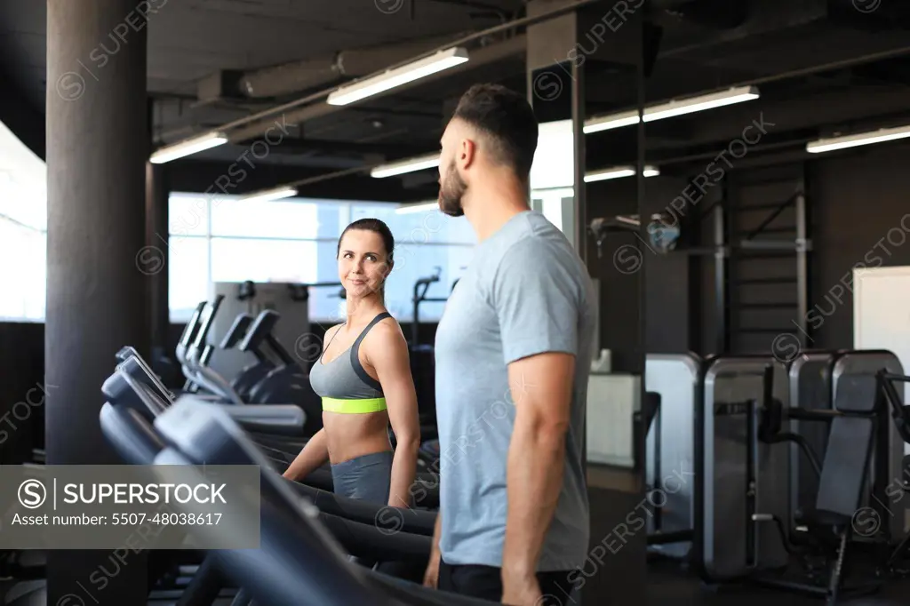 Healthy sport couple running on a treadmill in a sport gym.