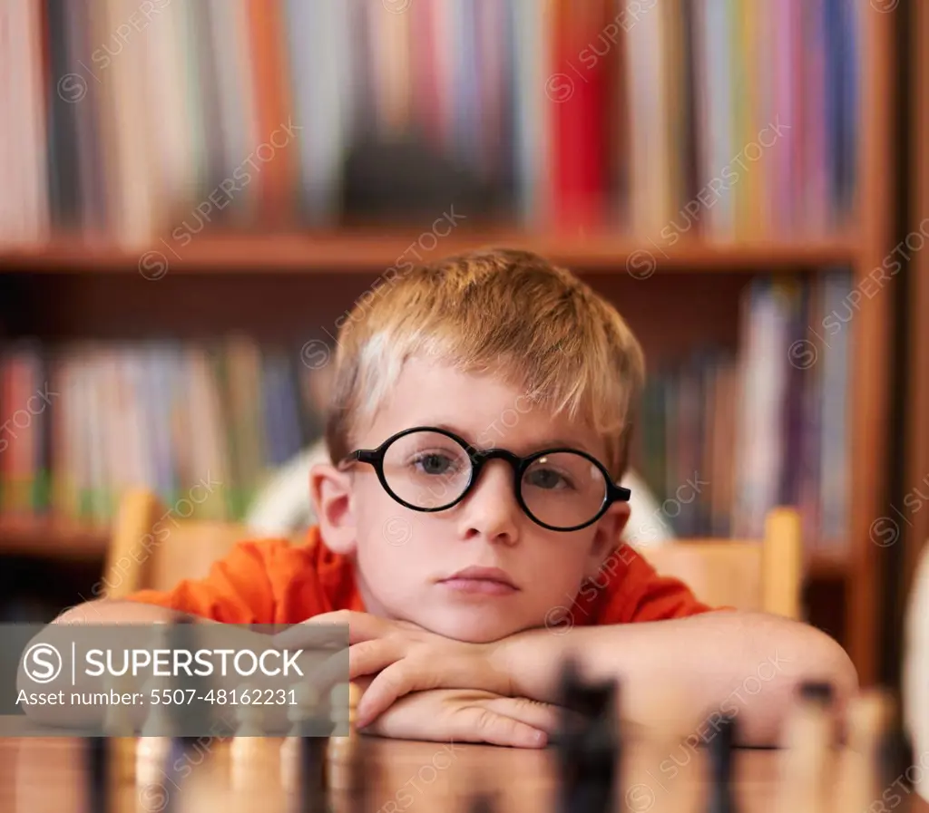 Portrait, chess and boy with glasses, bored and competition with training,  skills and clear vision. Face, person or kid with eyewear, tournament or  game with thinking, contemplation, ADHD or solution - SuperStock