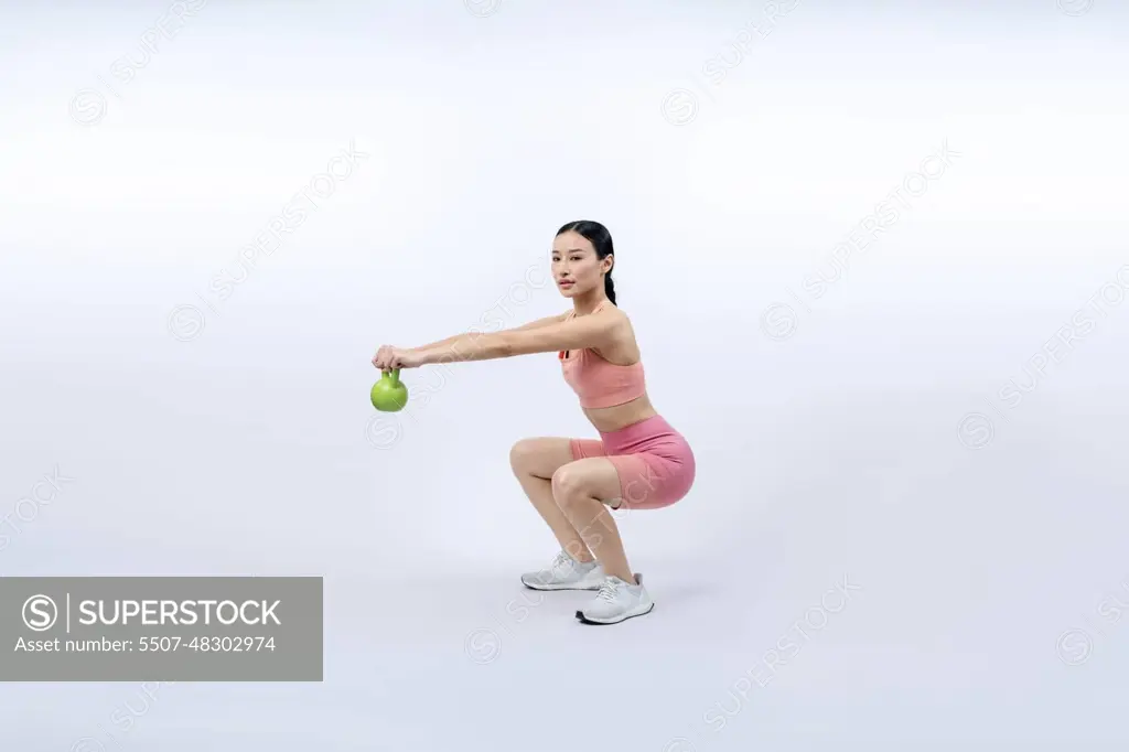 Vigorous energetic woman doing yoga with kettlebell weight exercise. -  SuperStock