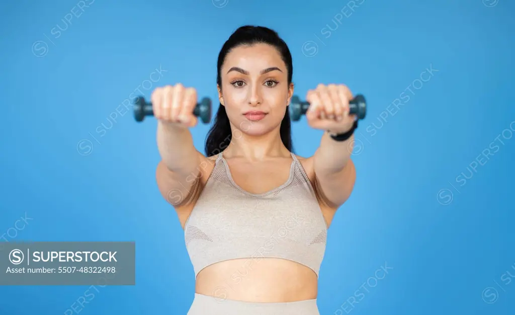 A healthy-looking young woman is training with dumbbells