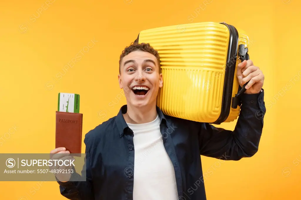 Excited young guy tourist with suitcase and passport