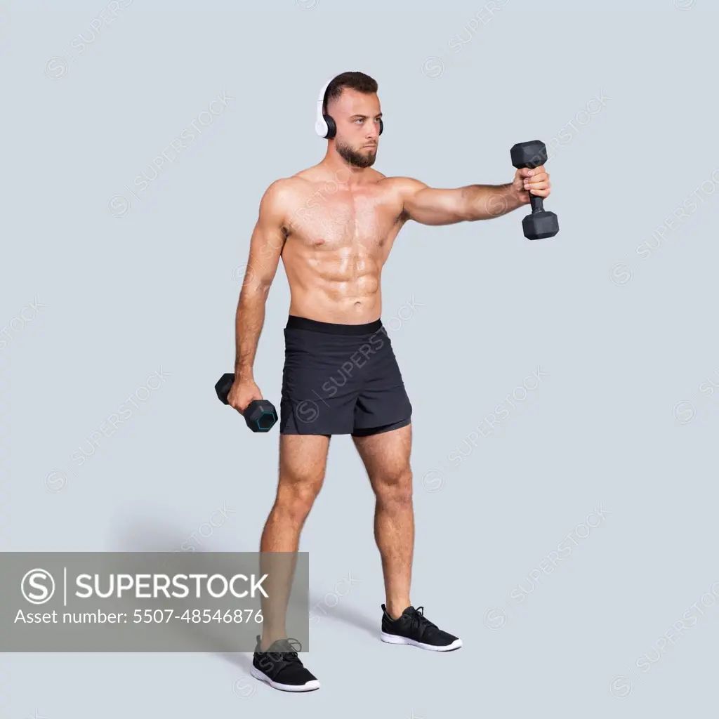 Strength exercises. Focused muscular young caucasian man athlete with naked  torso in wireless headphones - SuperStock