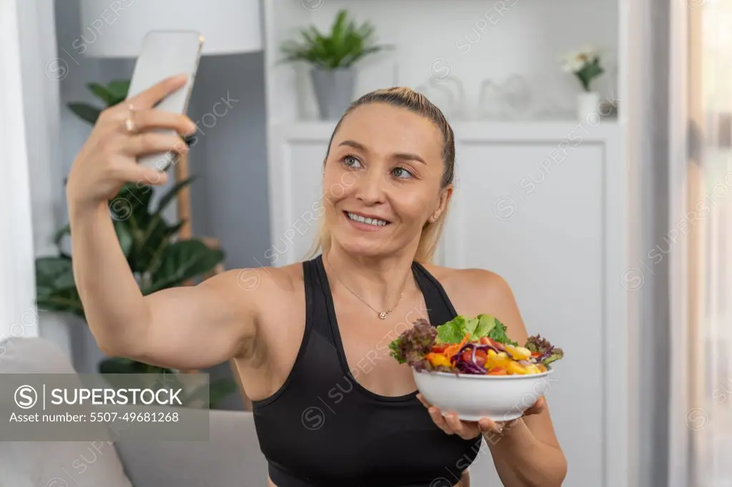 Healthy senior woman in sportswear taking selfie with vegan food. Clout