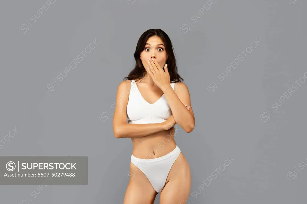 Shocked positive asian millennial woman in white underwear hand