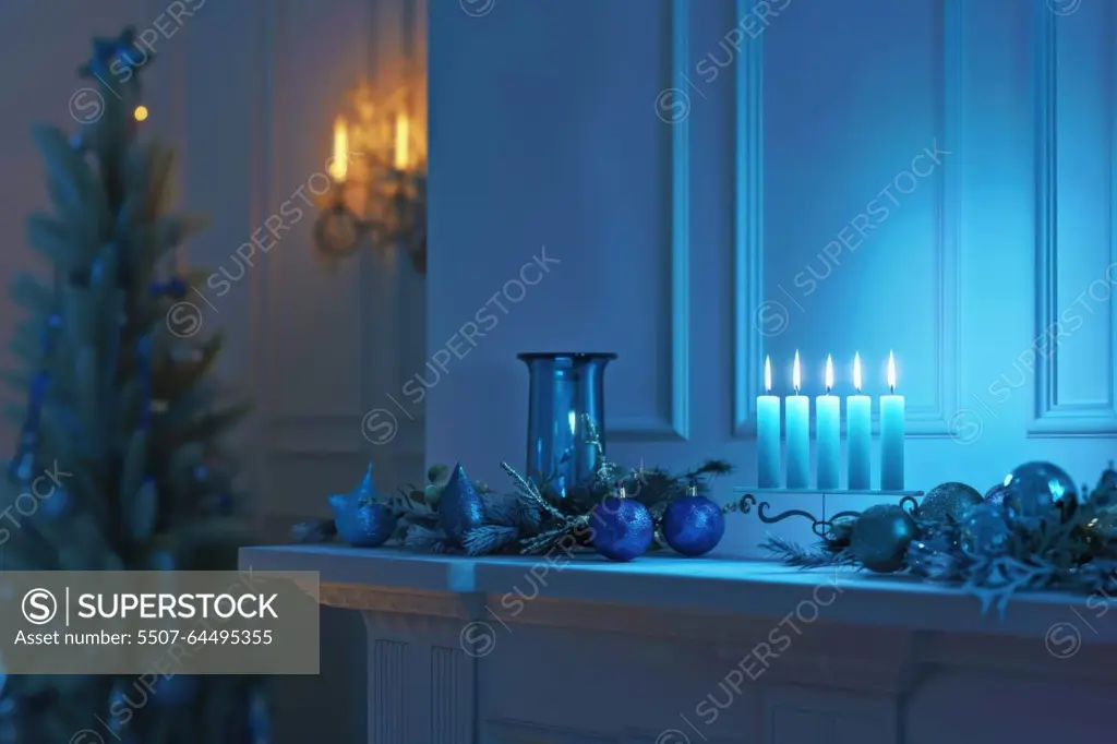 Modern menorah on a sleek white mantel adorned with blue and silver decorations. dimly lit room emphasizing the menorah's glow, creating a festive holiday ambiance. ideal for seasonal cards and home design.