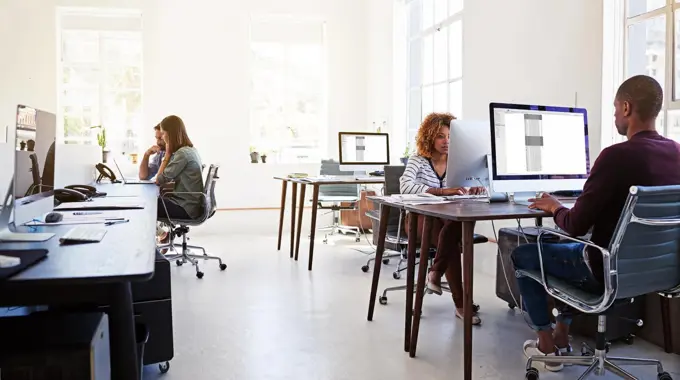 Working in an open plan office. Shot of colleagues working on their computers in an open plan office.