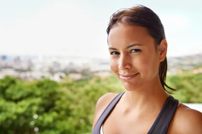 Healthy and happy. Portrait of an attractive young woman in sporty clothing standing on a blacony.