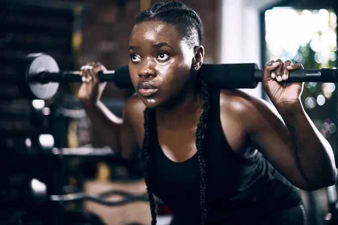 Fully focused. Full length shot of an attractive young female athlete lifting weights in the gym.