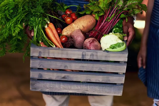 Eat healthy, stay healthy. Cropped shot of an unrecognizable farmer holding a crate full of fresh produce at his farm.