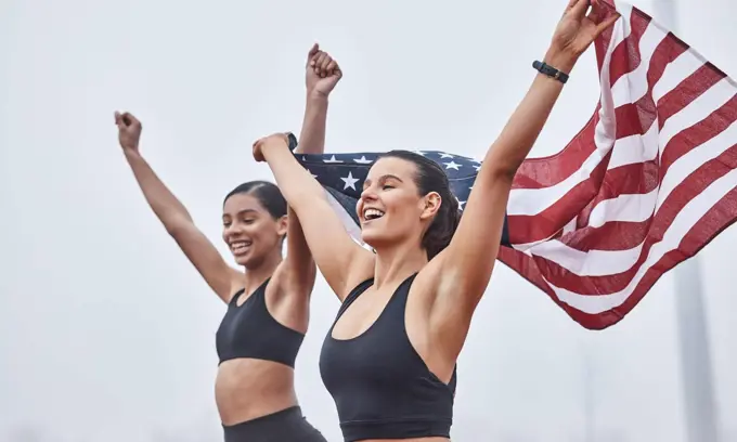 Women run the world. Shot of female athletes celebrating their win while holding a flag.