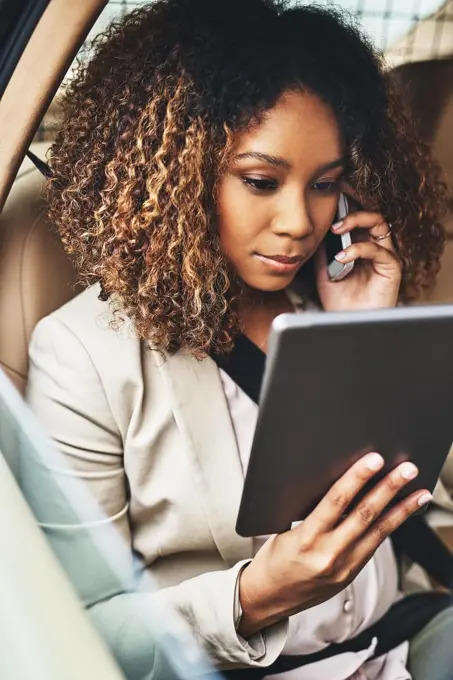 Getting things done even when shes commuting. Shot of an attractive businesswoman on a call and using a tablet during her morning commute.