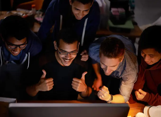 Were gonna win boys. Shot of a group of young man cheering at a monitor in a dark room.