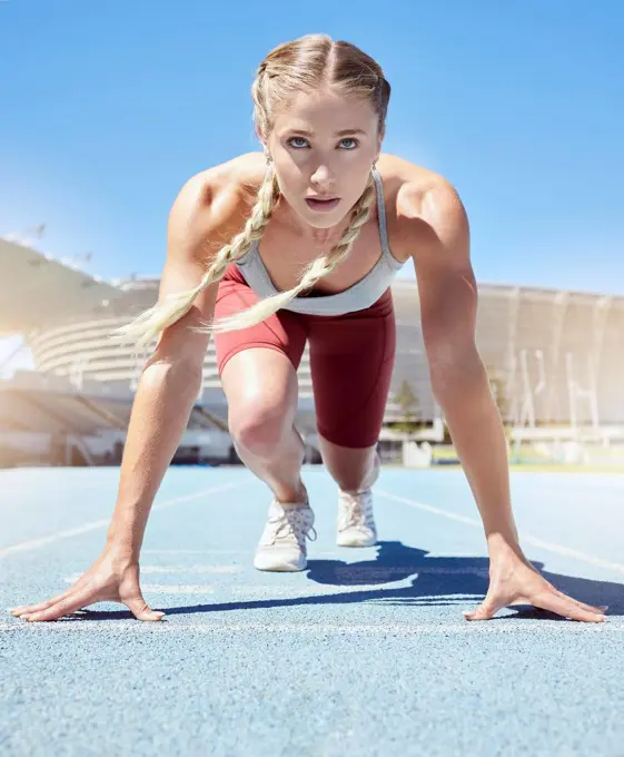 Serious female athlete at the starting line in a track race competition at the stadium. Fit sportswoman mentally and physically prepared to start running at the sprint line or starting block