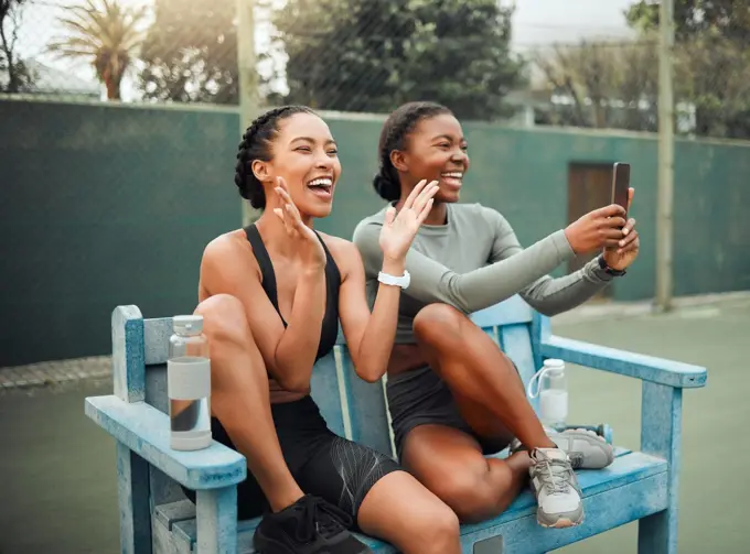 Cheering on their teammates. two attractive young female athletes sitting on a bench at a sports court watching a competition.