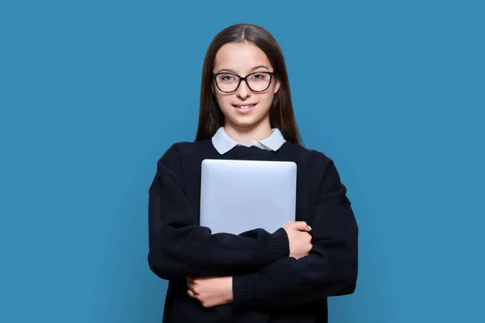 Teenage female student with laptop on blue color background