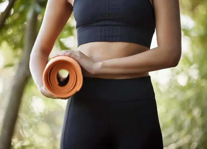 Off to yoga class. an unrecognizable young female athlete standing with her yoga mat outdoors.