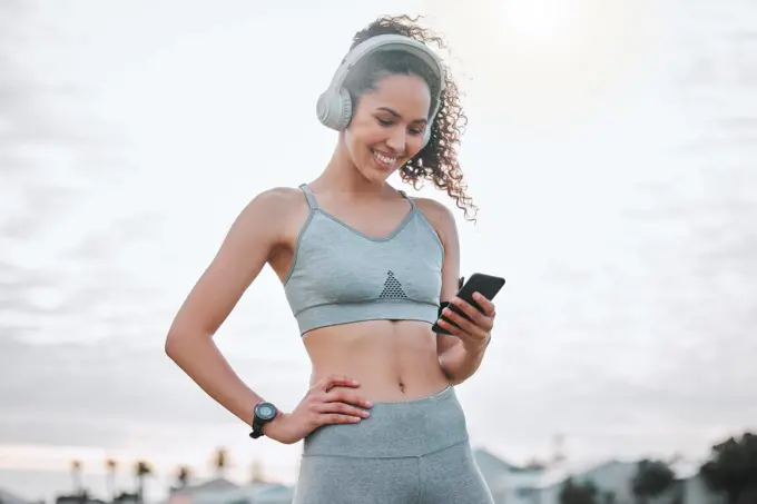 Tracking her personal progress. an attractive young female athlete exercising outdoors.