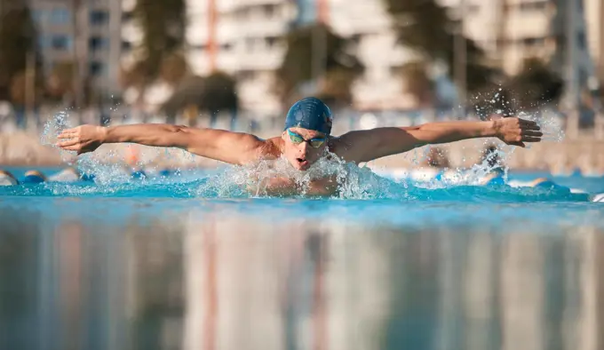 Aiming for a personal best. a handsome young male athlete swimming in an olympic-sized pool.