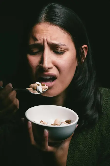 Check your diet. What is it doing to you. a young woman eating a bowl full of pills.