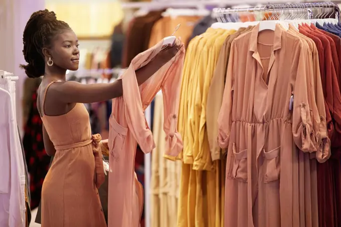 You cant keep buying the same thing. a young woman looking at items on a clothing rail in a boutique.