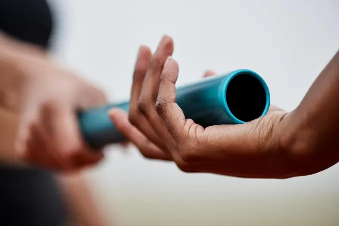 Take it and run. two athletes passing a baton during a relay race.