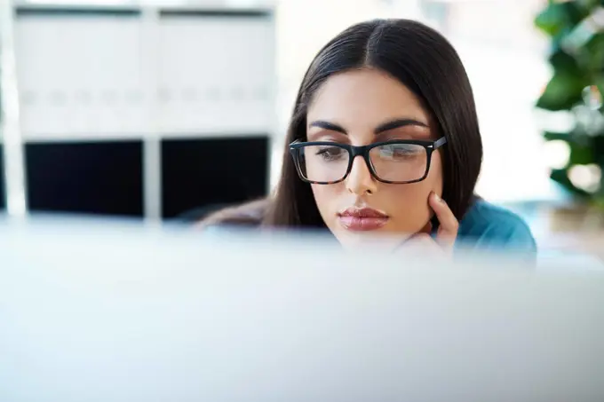 Work hard so you can achieve greatness. a young businesswoman working on a computer in an office.