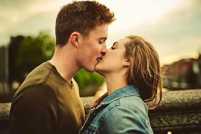 They are very much in love. a loving young couple sharing a kiss while out on a date.