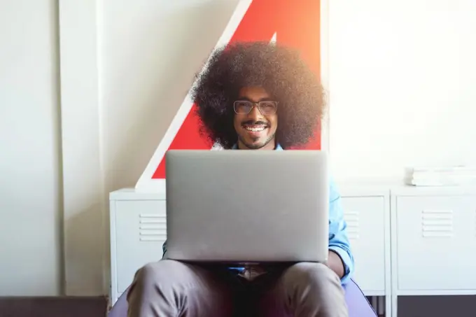 Getting his work done anywhere in the office. a young creative employee using a laptop in a modern office.