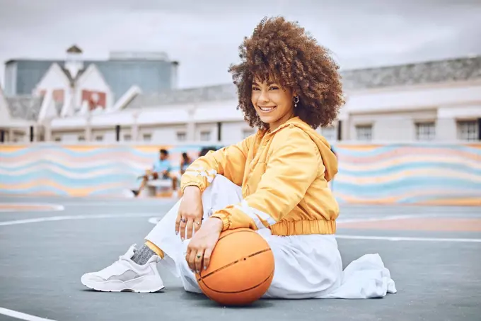 Beautiful, young and female basketball coach with an afro sitting on the court outside. Portrait of a professional, confident and healthy athlete woman in sports, health and fitness.