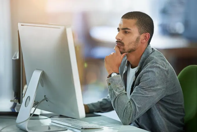 Immersed in his work. a young designer working at his computer in an office.