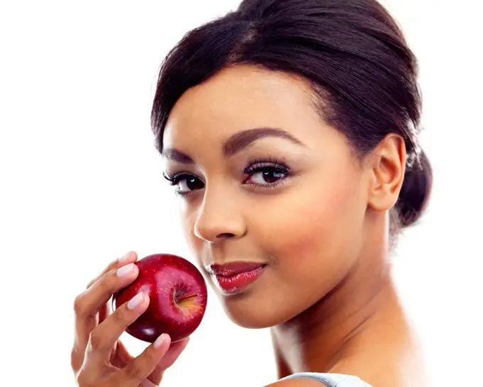 The perfect diet snack. A young woman holding an apple and smiling at the camera.