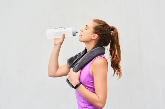 Water is an important part of exercise. an attractive young female athlete drinking water against a grey background.