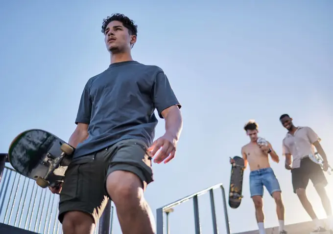 Skateboard, friends group and skatepark together, walking stairs and outdoor in summer sunshine. Skater diversity, happy and smile at metro park for sport, fitness and wellness with urban lifestyle