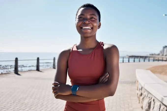 Fitness, happy black woman and thinking on beach sidewalk of vision, mindset and motivation for summer body goals, healthy exercise and wellness. Female sports athlete, smile and arms crossed at sea