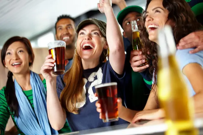 Drinks and sports with friends. A group of excited friends cheering on their favourite team at the bar.