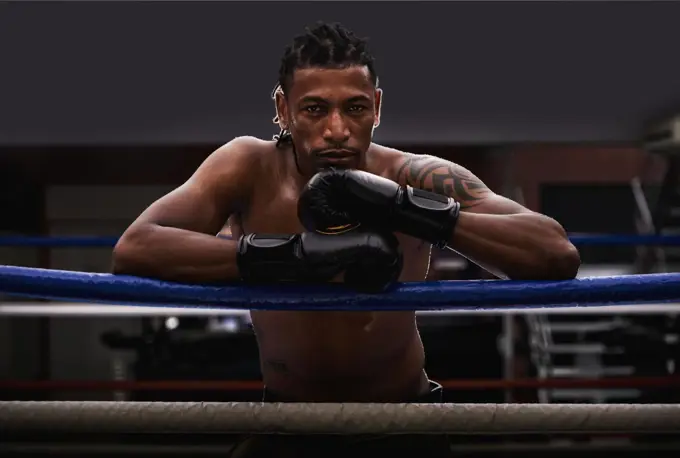 I own this ring. Portrait of a young boxer leaning on the ropes of a boxing ring.