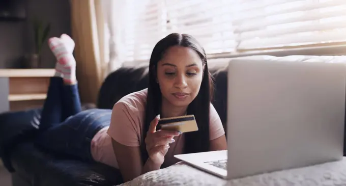 To buy or not to buy. a young woman relaxing while doing some online shopping at home.