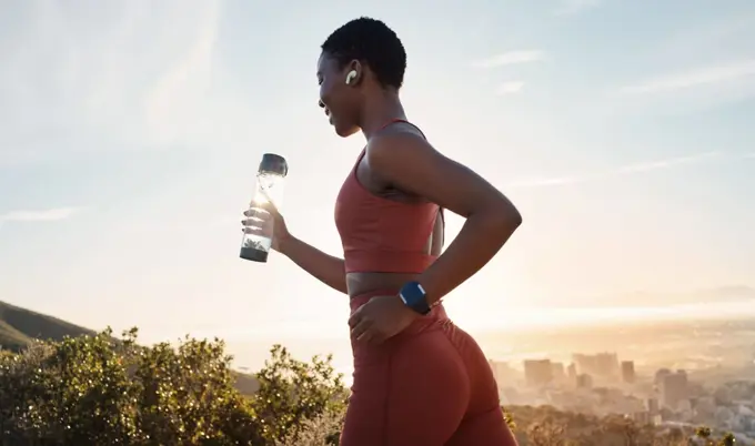 Workout, black woman or sunset with runner training, exercise for wellness, health or hydration. African American female, lady or athlete with water bottle, practice for marathon or fitness in nature