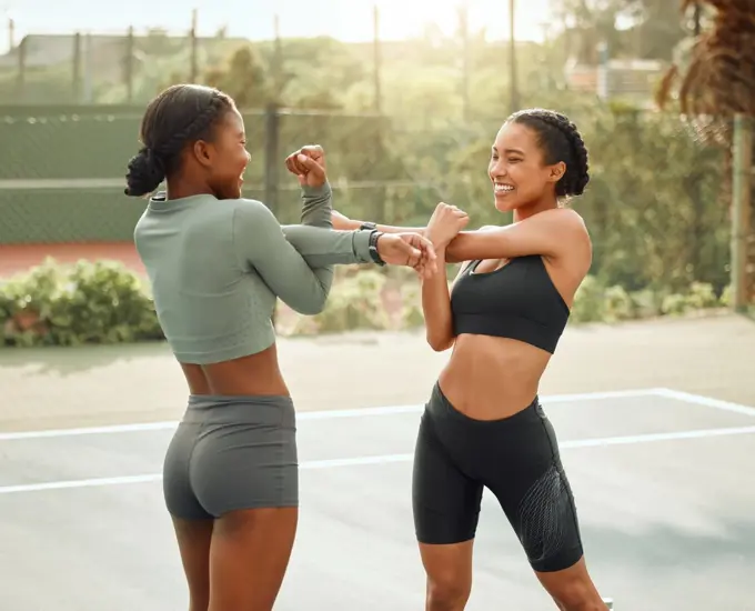 Stay warm. two attractive young female athletes warming up outside before beginning their workout.